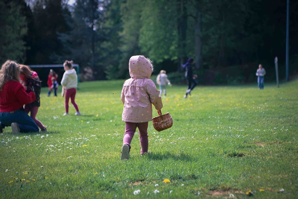 Enfant de dos avec un panier et qui cherche des œufs de pâques