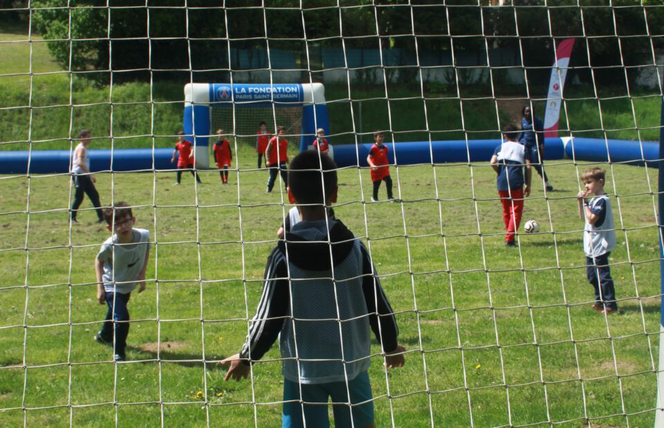 Un enfant de dos dans une cage de football pendant un match