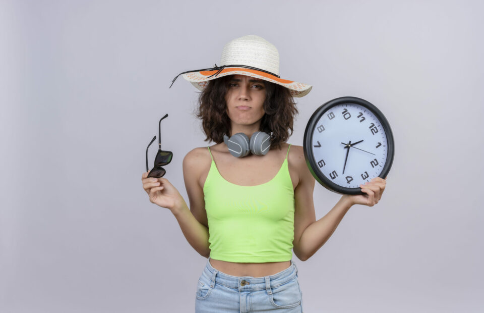 Femme avec un chapeau tenant une horloge et des lunettes de soleil